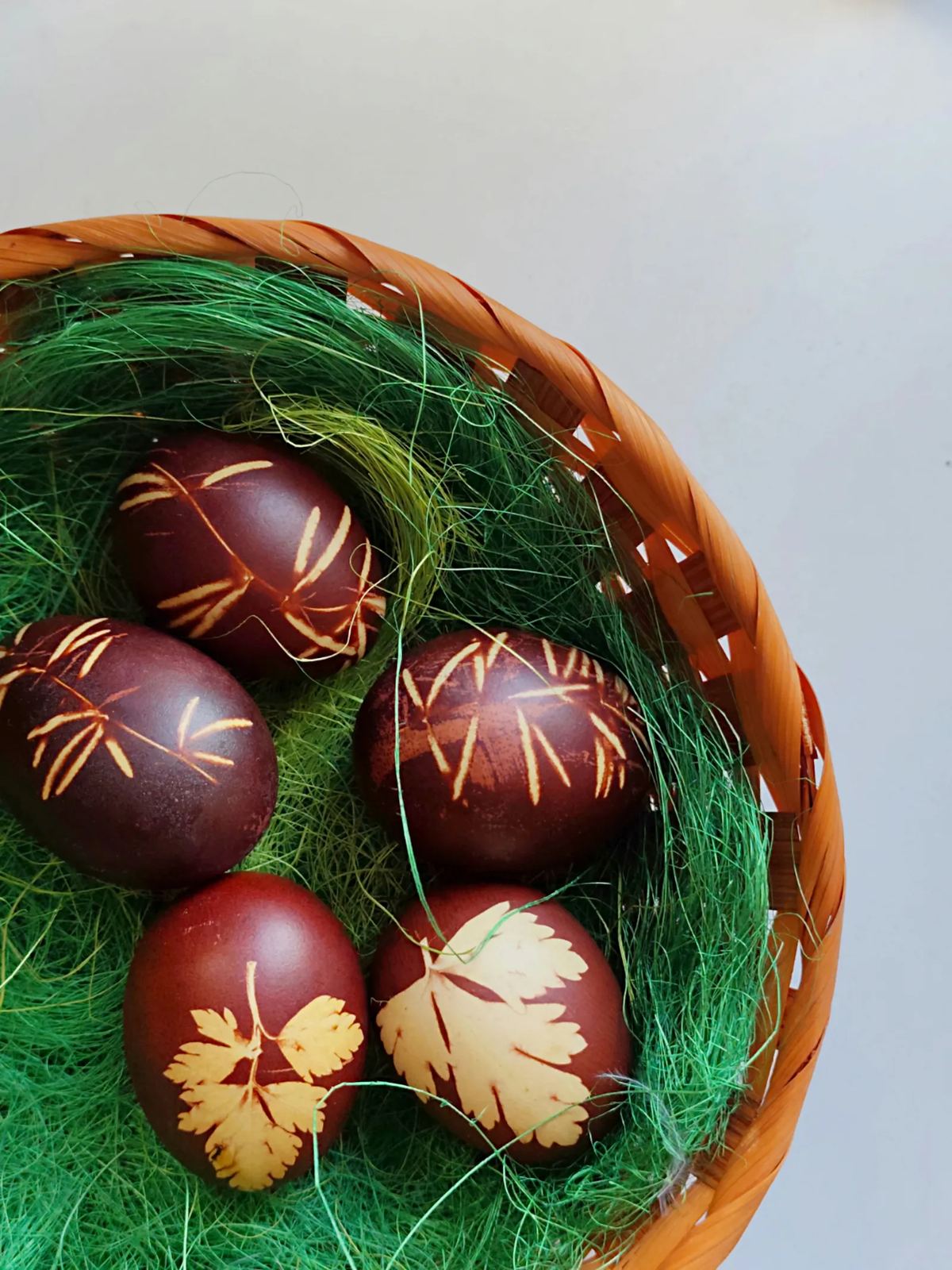 Hand-painted Romanian Easter eggs with leaf-print patterns in a basket